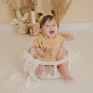 Bebê sentada em um banquinho sorrindo