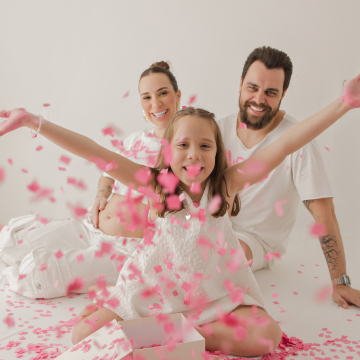 Mãe, pai e filha brincando com pétalas rosas